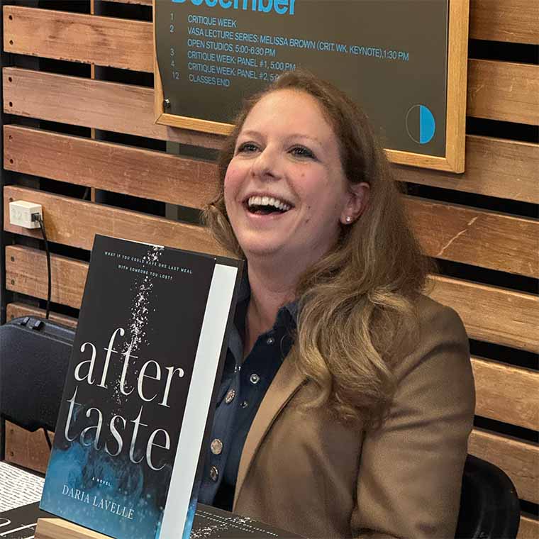 smiling person seated behind stack of books